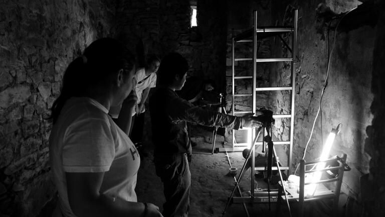 Black and white photo of students setting up to take photographs of underground chambers at Stobi.