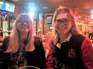 Photograph of two students in a bar with sticky notes attached to their foreheads as part of a game.
