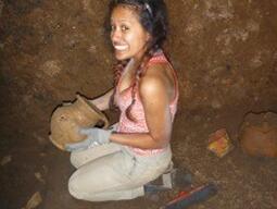 Photograph of a student holding an intact vessel that she has discovered at the Caere excavation site.