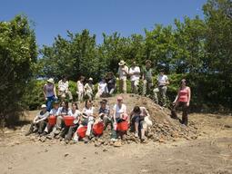 Caere dig team posing on a mound of excavated dirt.