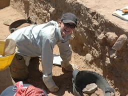 Student working carefully to clear a floor at Humayma excavation site.
