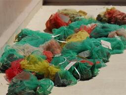 Mesh bags of cleaned pottery drying on a sunbathed roof.