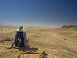 Student having a seat and taking a rest, overlooking the desert views near Humayma excavation site.
