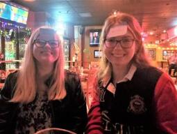 Photograph of two students in a bar with sticky notes attached to their foreheads as part of a game.
