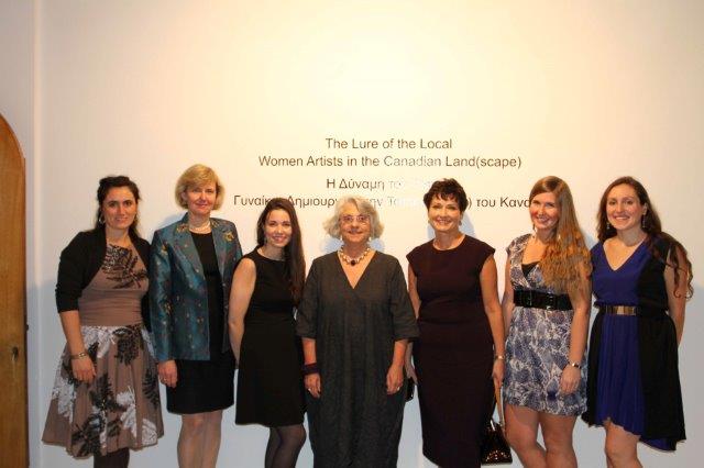 Seven people smiling in front of a wall with text on it