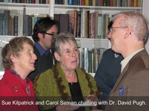 Three people having a conversation in front of a book case