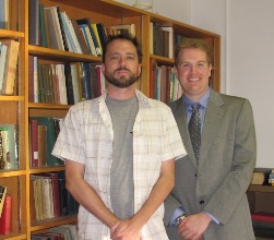 Two people standing in front of a book case smiling