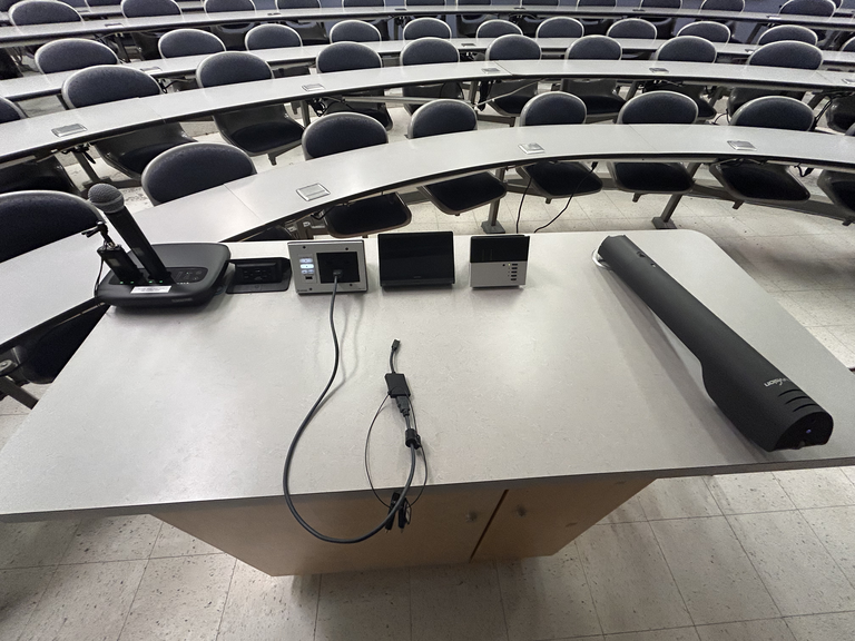 Top down view of the podium. The podium is equipped with a document camera, lecture capture, wireless presentation, and a set of microphones. The podium is not height adjustable.