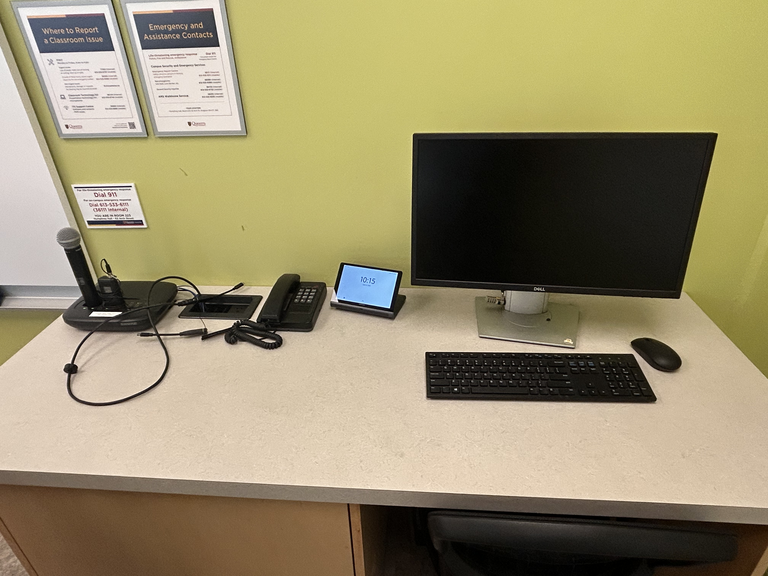 Top-down view of podium. Microphones and telephone on the left; touch panel control system at center; PC, keyboard and mouse on the right.