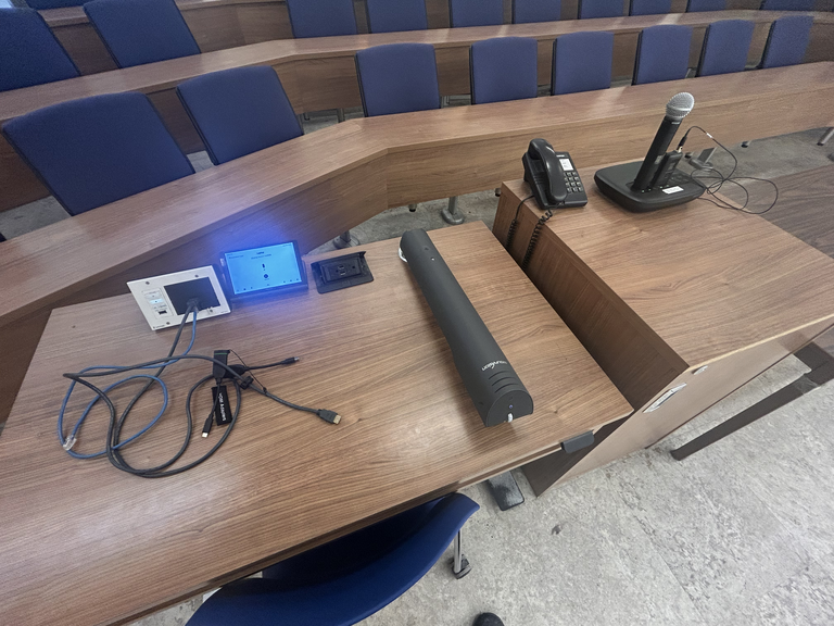 Top-down view of podium. Touch panel control system on the left; document camera at center; telephone and microphone on the right.
