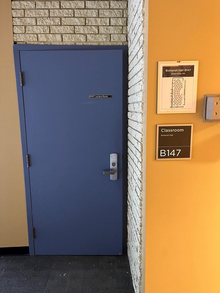 Image of the doors that enter Botterell Hall Room B147. The door has a metal handle on the right side. The door does not have automatic control.