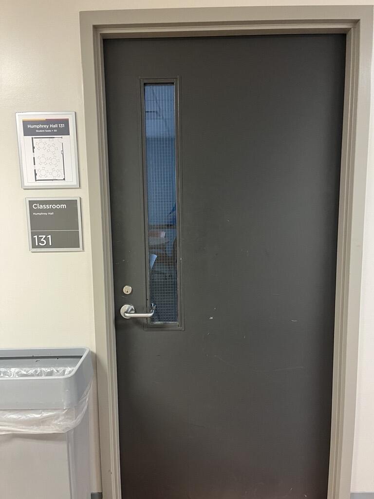 The entryway of room 131 in Humphrey Hall is a single grey door with a silver handle on the left side of the door. 