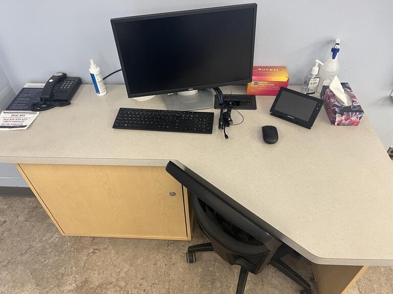 Top down view of the podium. The podium has a room PC, a set of display cables, and a telephone. The podium is not height adjustable but is accessible for instructors.
