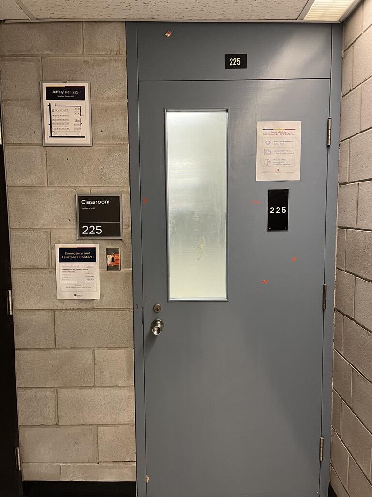 Door to enter Jeffery Hall room 225. The door is light grey and has a knob on the left side.