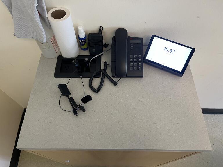 Top-down image of the podium. The podium is equipped with a set of connection cords to present media in the room.