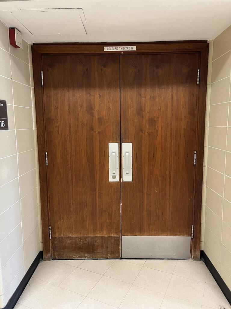 Entryway to room 301B in Stirling Hall. The double door has two pull handles in the center. There is no automatic operator.