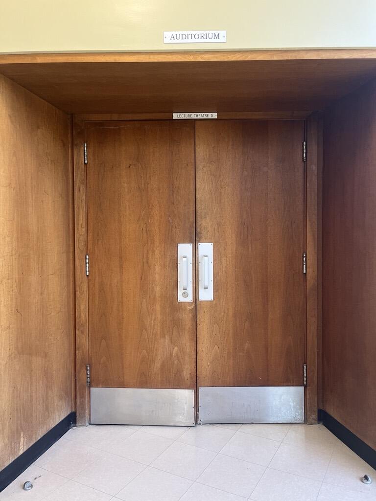 The entryway to the AUD in Stirling Hall. The double door has pull handles in the center. There is no automatic operator.