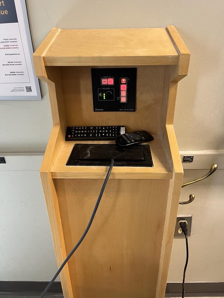 View of the podium. The podium has display cables, and a control panel to manage inputs. The podium is not height adjustable, but the podium is accessible for instructors.