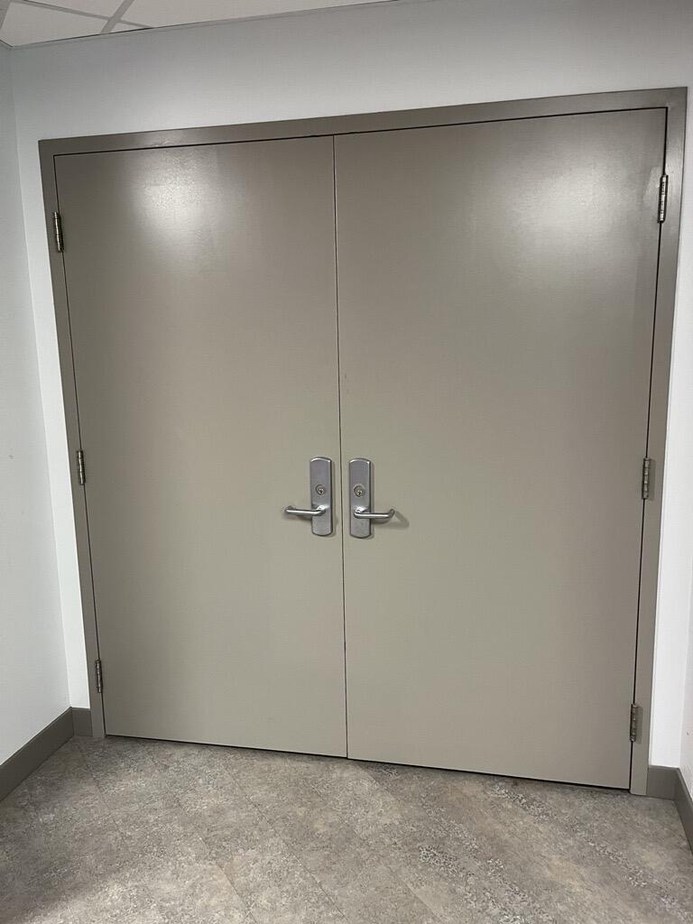 The entryway of the auditorium in Walter Light Hall is a white double door with levers in the middle on each door. 