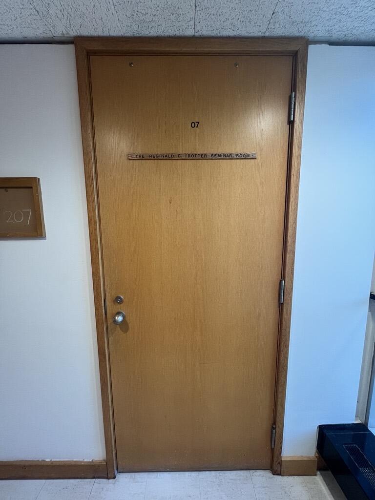 The entryway of room 207 in Watson Hall is a wooden door with a doorknob on the left side.