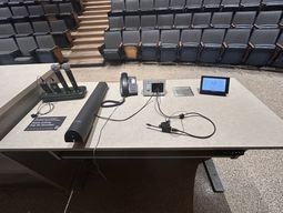 Top-down view of podium. Microphones and document camera on the left; telephone at center; and touch panel control system on the right