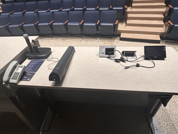 Top-down view of podium. Microphones and telephone on the left; touch panel control system on the right.