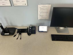 Top-down view of podium. Microphones on the left; telephone and touch panel control system in center; PC, keyboard and mouse on the right. 