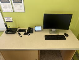 Top-down view of podium. Microphones and telephone on the left; touch panel control system in center; PC, keyboard and mouse on the right. 