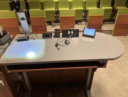 Top down view of the podium. This podium is equipped with a set of microphones, a document camera, lecture capture and wireless presentation. The podium is height adjustable. 