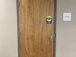 Entryway door to Biosciences complex, room 2109. The door has a handle on the right side.