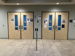 Image of doors that enter to room 1101 in Biosciences Complex. There are two sets of double doors that have metal handles at the center of the doors. The entrance can be controlled by an automatic door opener. 