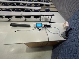 Top down view of the podium. The podium is equipped with a set of microphones, a document camera, lecture capture, and wireless presentation. This podium is not height adjustable.