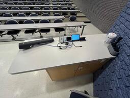 Top down view of the podium. The podium is equipped with a document camera, lecture capture, and a set of microphones. The podium is not height adjustable.
