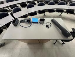 Top down view of the podium. The podium has a document camera, lecture capture, a set of microphones, and a display cable.