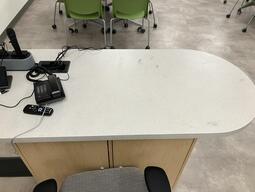 Top-down view of the instructors podium. The podium is equipped with a phone and a set of microphones. The podium is not height adjustable.