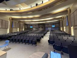 View of the classroom from the instructor’s podium. There are multiple rows of chairs for students, with aisles to access seating throughout the auditorium. This classroom is accessible for instructors.