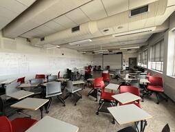 View of the classroom from the student's view. There are multiple chairs with tablets attached for students. This classroom is accessible for students.
