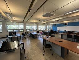 Instructors view from the podium. Tables throughout the room each have 8 seats. The room is accessible for students and for the instructor.