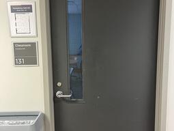 The entryway of room 131 in Humphrey Hall is a single grey door with a silver handle on the left side of the door. 