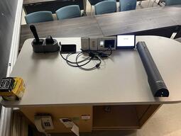 Image of the podium at the front of the classroom. This podium is not movable or height adjustable. This podium is not accessible. There is a document camera and a set of microphones on the podium.
