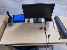 Top down view of the instructor’s podium. The podium is equipped with a computer, a document camera and microphones. The podium is height adjustable and accessible for the instructor.