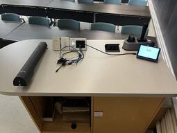 Top down view of the podium. This podium is not movable or height adjustable. This podium is not accessible. The podium is equipped with a document camera, lecture capture and a set of microphones.
