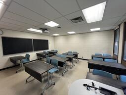 View of the classroom from the instructor’s podium. There are three rows of tables with chairs for students, which can be arranged according to instructor’s preference. This classroom is accessible for instructors.