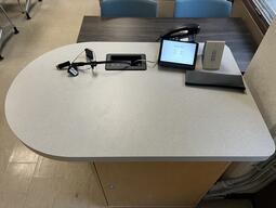 Top down view of the podium. The instructor’s podium is equipped with a set of cabled for media display and a telephone. The room is accessible for instructors.