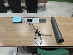 Top-down view of the instructor's podium. The podium is equipped with a document camera, lecture capture, lighting control, an outlet and a set of connection cords to present media on the projector.