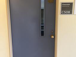 The entryway of room C508 in Mackintosh Corry Hall is a blue door with a doorknob on the right side.