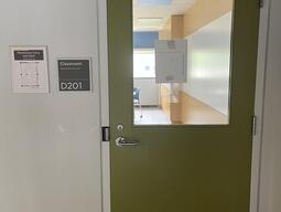 Door to enter room D201 in Mackintosh-Corry Hall. The door has a lever on the left side. There is an automatic operator.