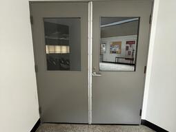 Doors entering the room D216 in Mackintosh-Corry Hall. The doors are a set of double doors and do not have an automatic door opener.