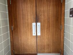 The entryway to room 301C in Stirling Hall. The double door has pull handles in the middle. There is no automatic operator.