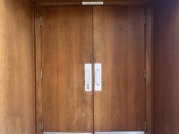 The entryway to the AUD in Stirling Hall. The double door has pull handles in the center. There is no automatic operator.
